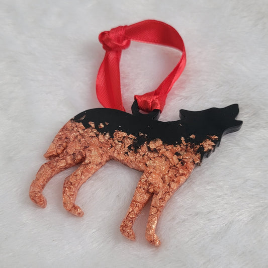 Wolf shaped epoxy resin ornament, made with copper foil flakes and black pigment and a bright red ribbon attached.