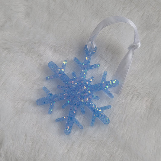 Snowflake shaped epoxy resin ornament, made with light blue iridescent glitter and a white ribbon attached.