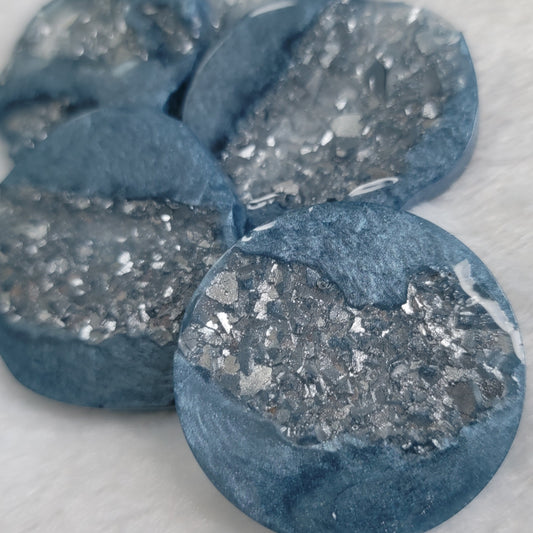 Close up of round epoxy resin pieces made with ice blue mica pigment and silver crystalline texture insets.