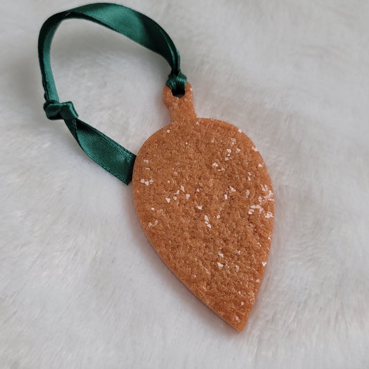 Drop shaped epoxy resin ornament that has a crystalline texture, made with golden bronze pigment and a dark green ribbon attached.