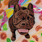 Portrait of a brown brindle French bulldog wearing rainbow fairy wings made with layers of adhesive vinyl on a canvas. The background has orange swirled acrylic paint and is adorned with shiny vinyl orange slices and leaves.