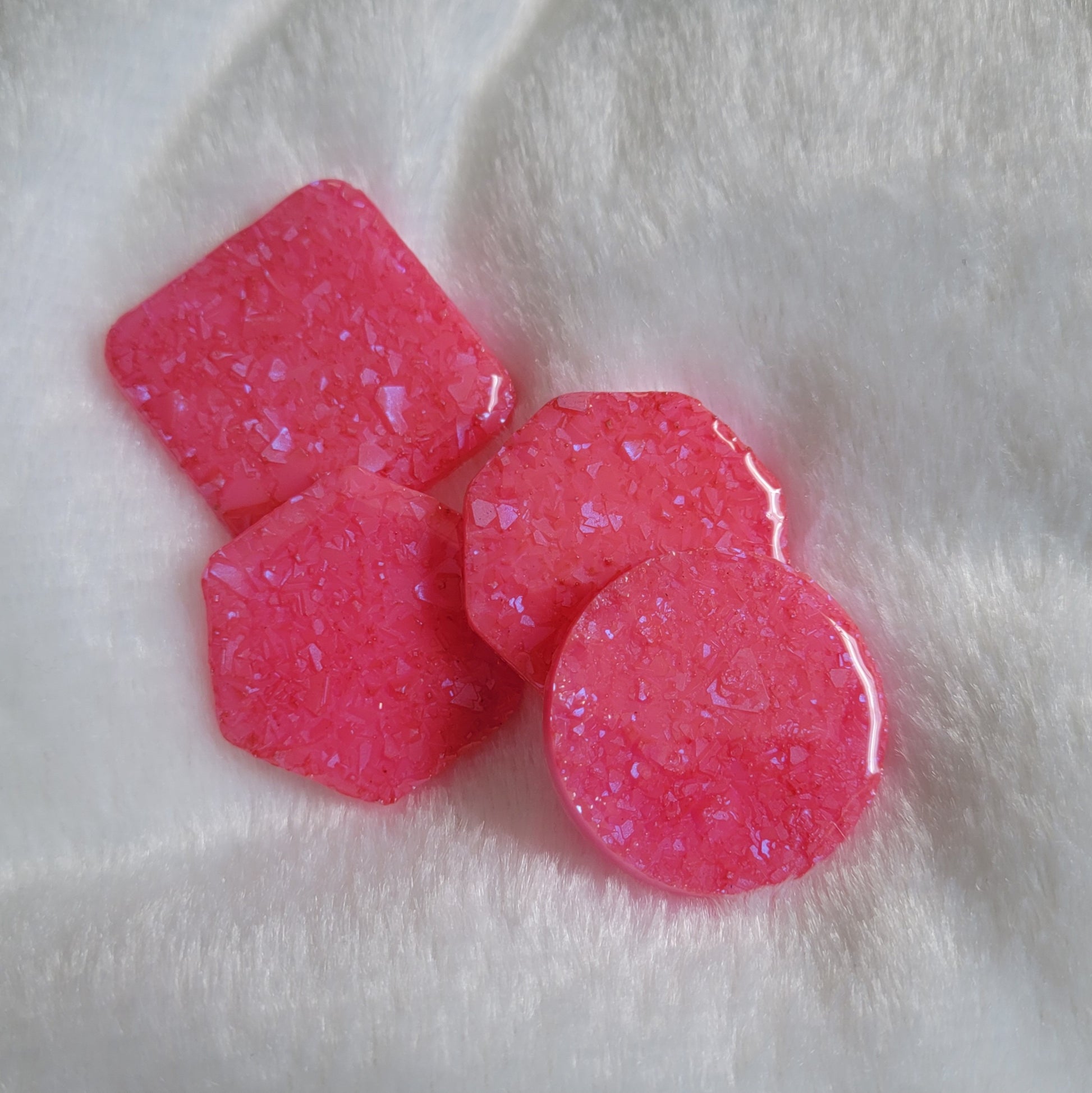 Four bright pink epoxy resin pieces with crystalline texture, one each - square, hexagon, octagon and round.