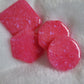 Four bright pink epoxy resin pieces with crystalline texture, one each - square, hexagon, octagon and round.