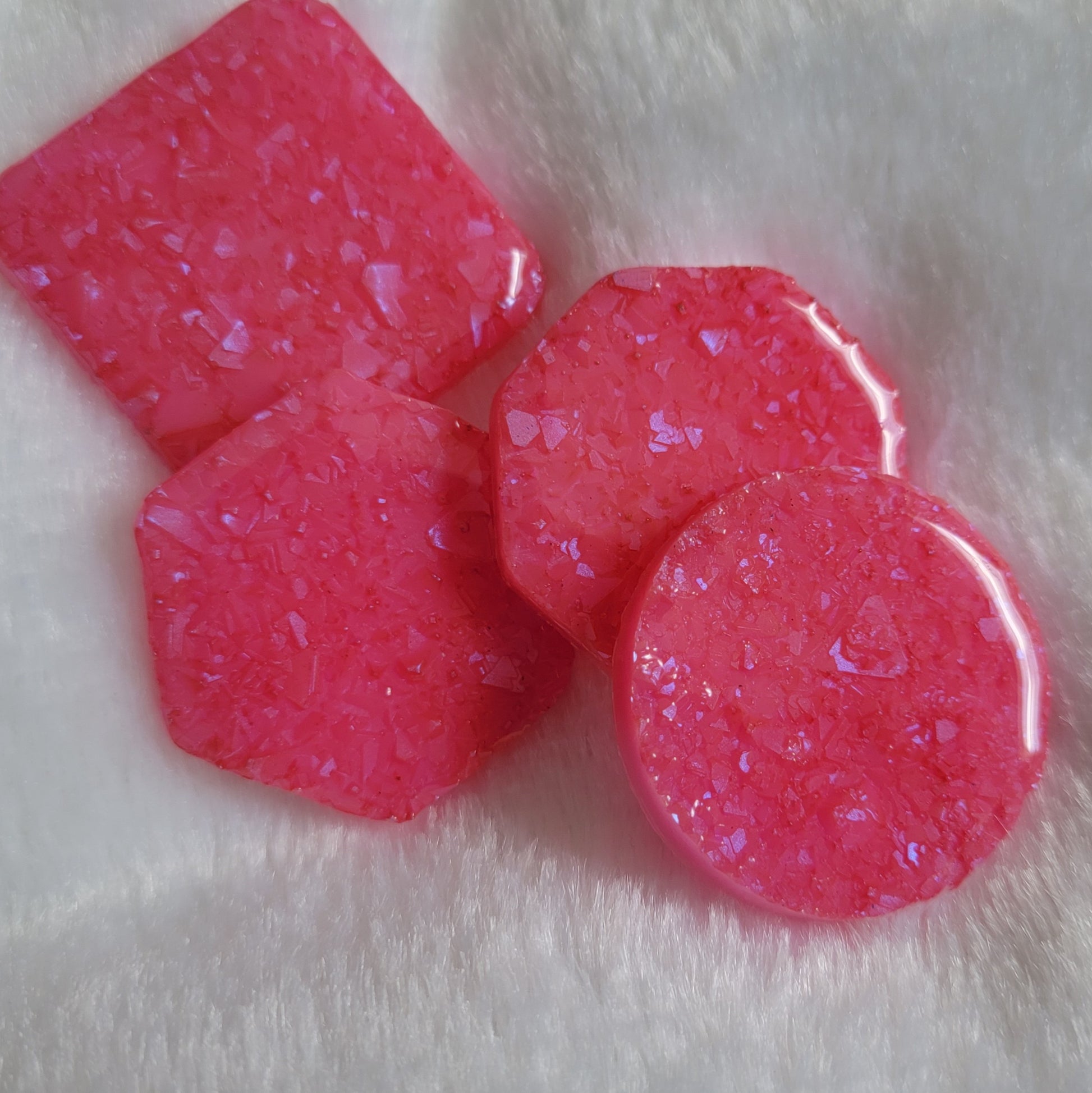 Four bright pink epoxy resin pieces with crystalline texture, one each - square, hexagon, octagon and round.