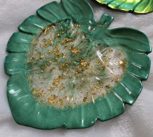 Monstera leaf shaped decorative dish made from epoxy resin, translucent center with gold foil flakes and deep hunter green edges.