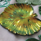 Monstera leaf shaped decorative dish made from epoxy resin, iridescent gold coating over dark green.