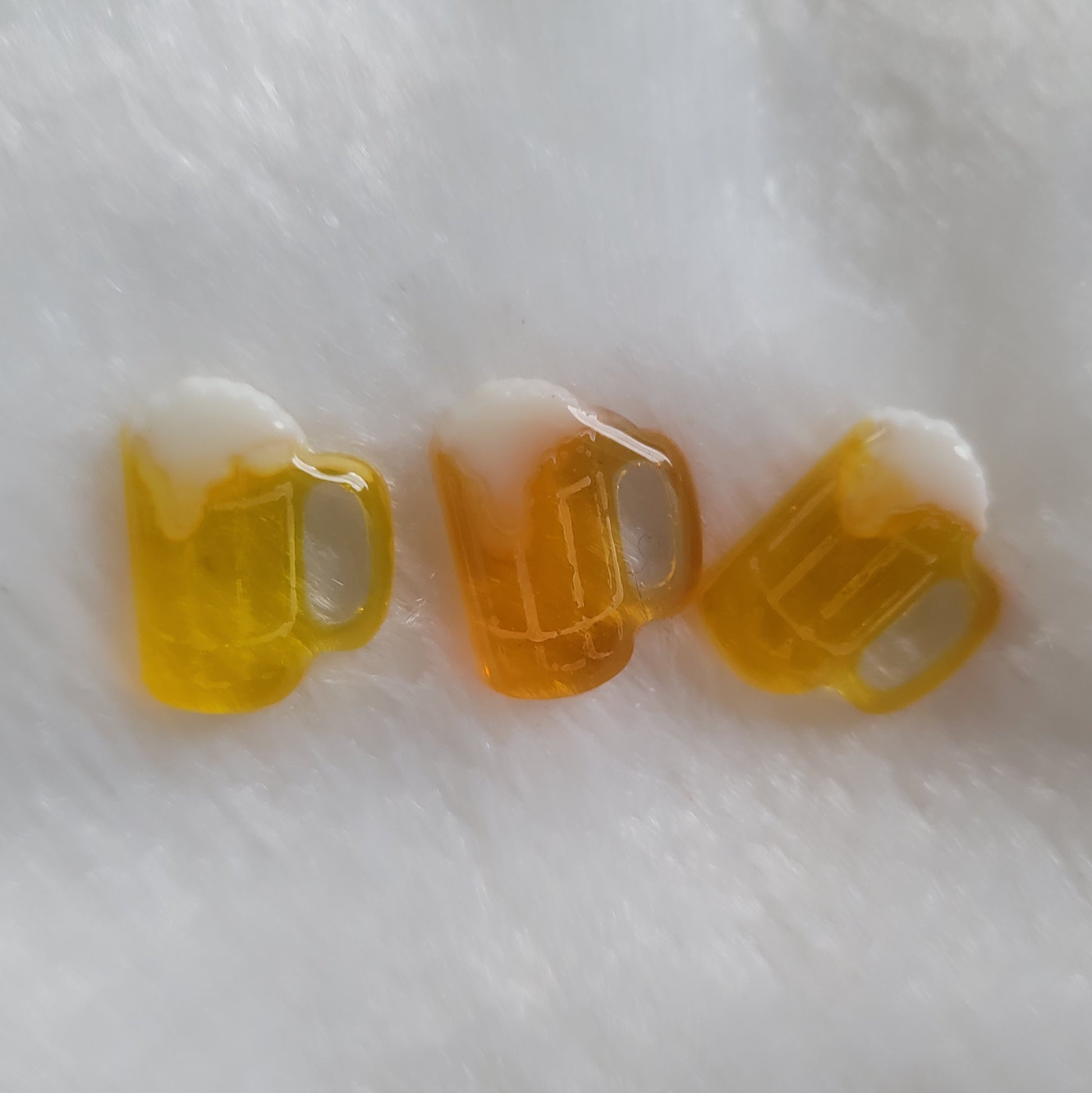 Three small beer mug shaped resin pieces in varied shades of amber.