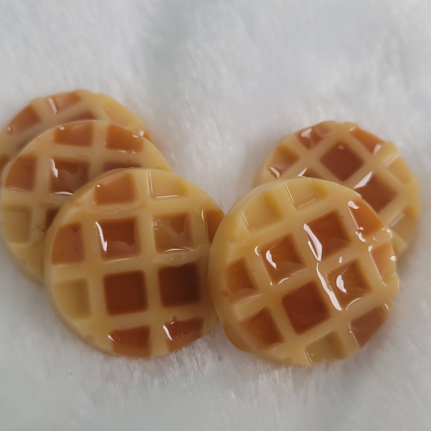 Five waffle shaped resin pieces, decorated to look like waffles topped with maple syrup.
