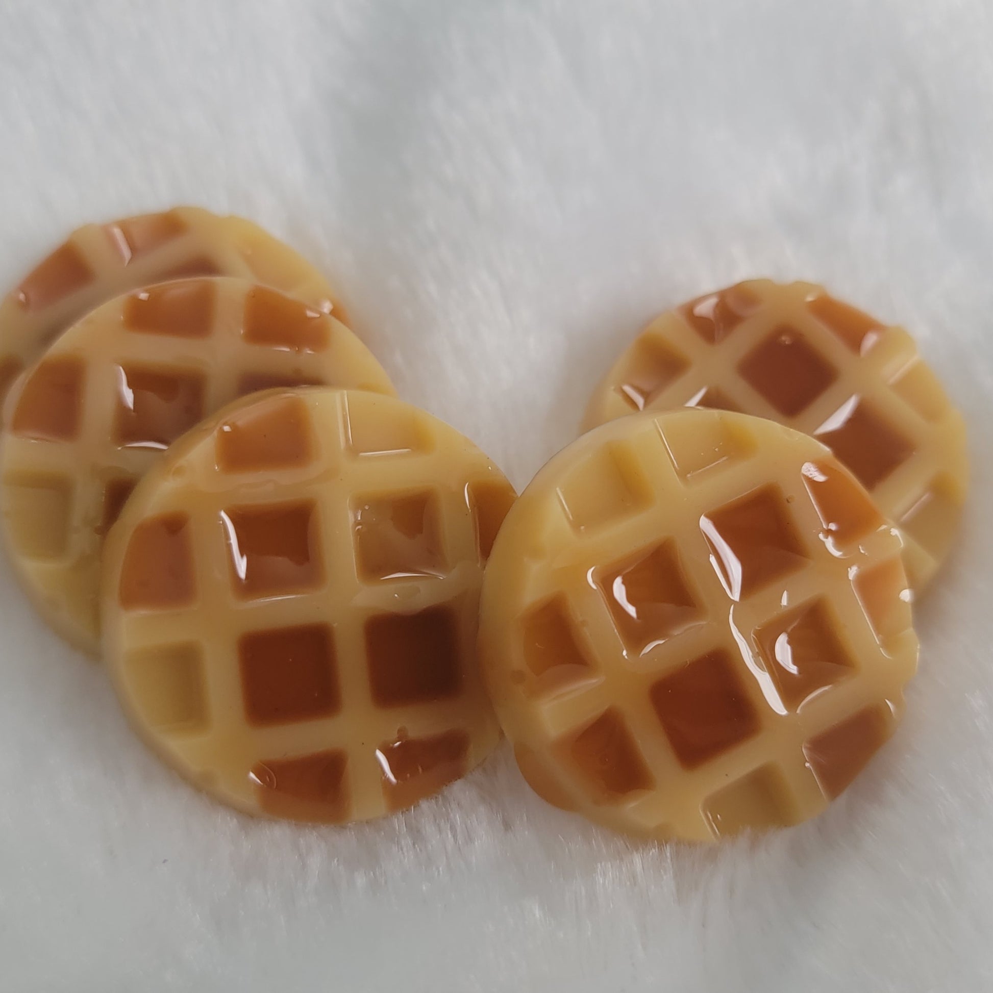 Five waffle shaped resin pieces, decorated to look like waffles topped with maple syrup.