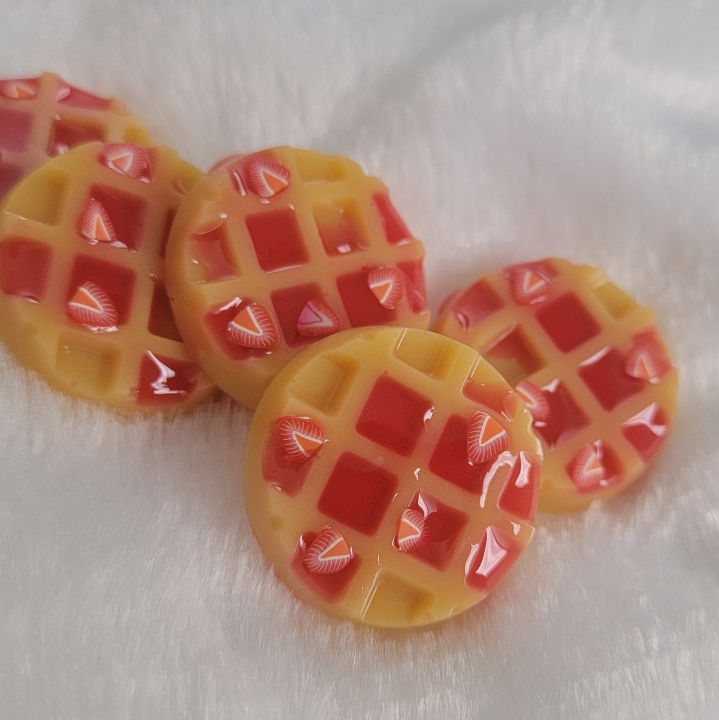 Five waffle shaped resin pieces, decorated to look like waffles topped with strawberries and jam.