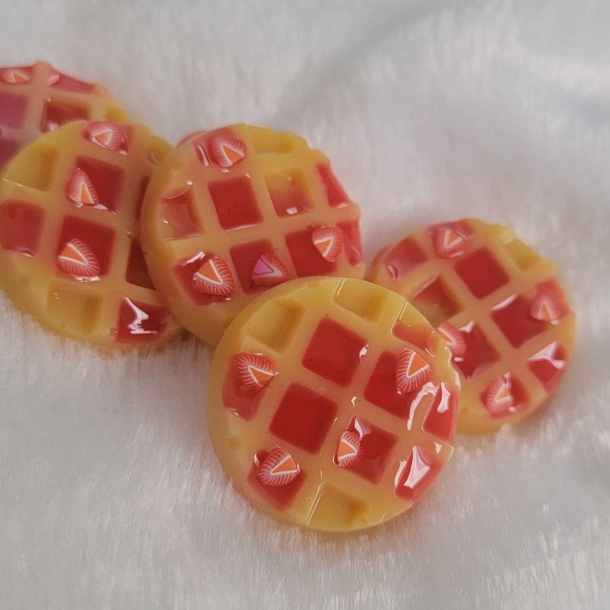 Five waffle shaped resin pieces, decorated to look like waffles topped with strawberries and jam.