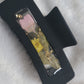 A black 4-inch claw clip with a long stem pink flower and small yellow blossom cast in resin within an open space in the hair clip.