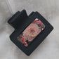 A black 2-inch claw clip with lavender and pink pressed flowers cast in resin within an open space in the hair clip.
