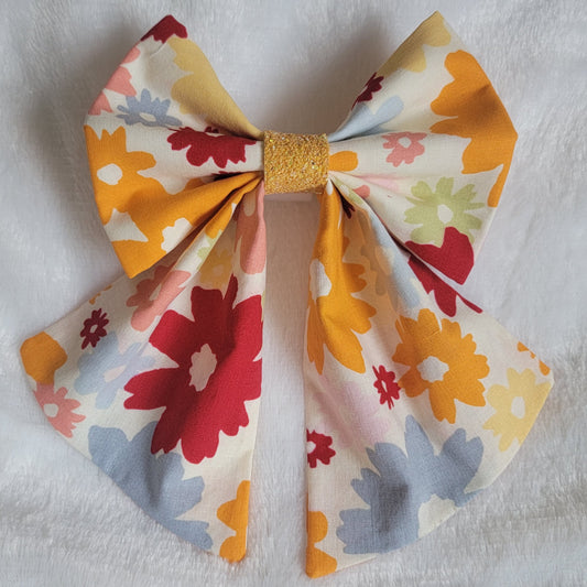 A handmade pet bow with a warm retro floral cotton print in light orange, pink, red, green, blue and yellow. Features  light orange glitter center, sailor bow style with long showy tails.