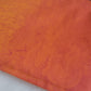 Close up of the orange ombre fabric, on a part with more deep orange, showing the sky print which has suns and clouds and seabirds and stars in contrasting shades of orange.