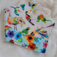 Handmade bandana featuring colorful tropical birds and floral prints patched together in stripes, unique on each side. Displayed with the corners folded under, on a white background.