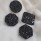 Four black crystal textured epoxy resin pieces - circle, octagon, square, and hexagon shaped - displayed on a white background