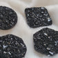 Four black crystal textured epoxy resin pieces - circle, octagon, square, and hexagon shaped - displayed on a white background