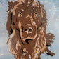 Vinyl art of a brown newfoundland dog on a canvas painted with light blue acrylic paint, adorned with snow glitter and sealed in epoxy resin.