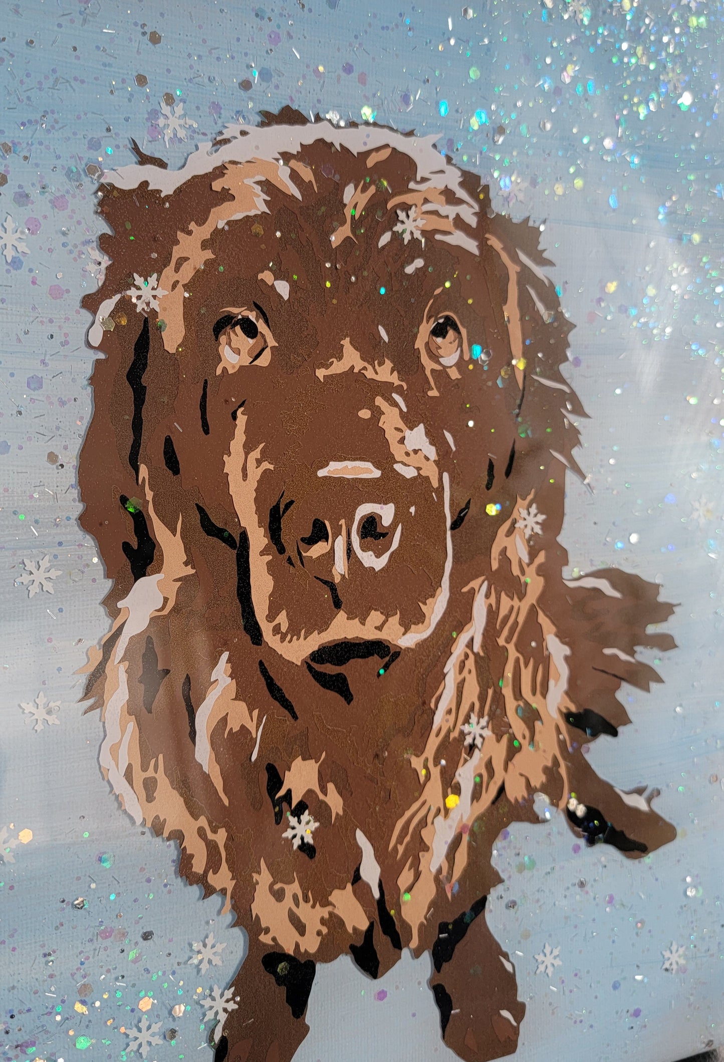 Vinyl art of a brown newfoundland dog on a canvas painted with light blue acrylic paint, adorned with snow glitter and sealed in epoxy resin.