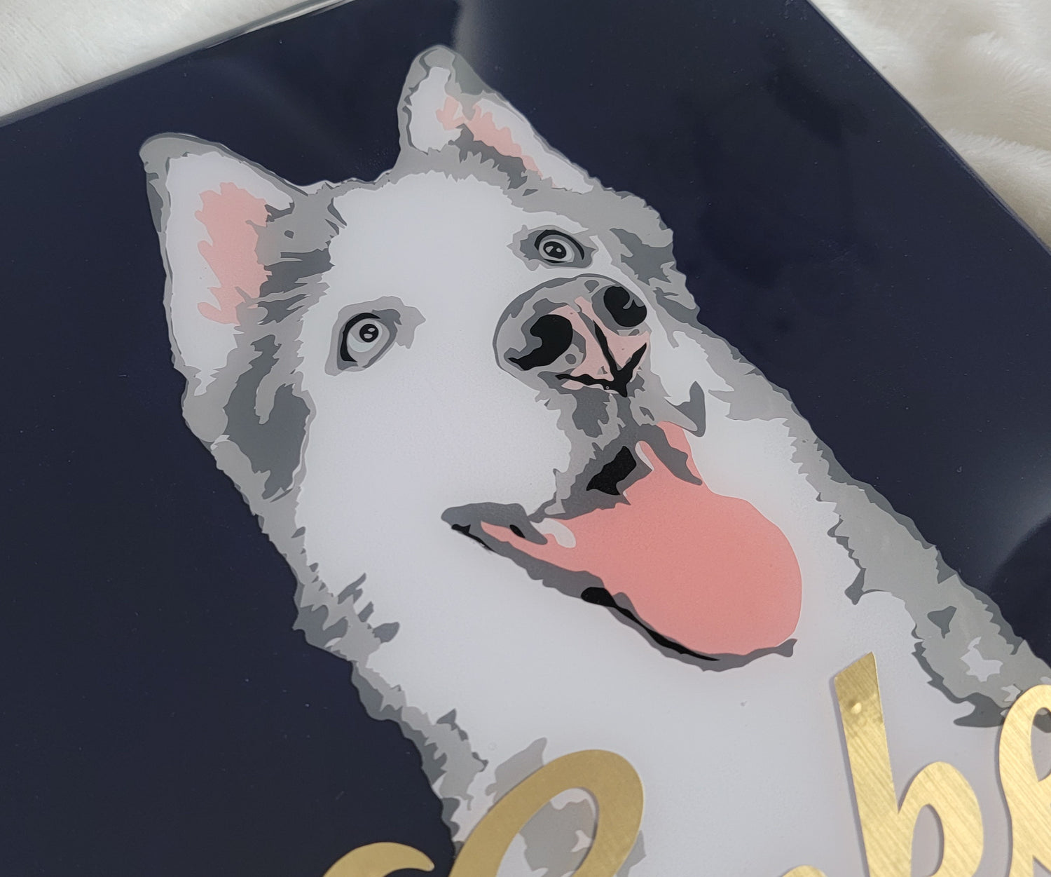 Portrait of a grey and white husky dog made with vinyl on a navy blue canvas background, sealed in epoxy resin with chrome gold vinyl name across the front.