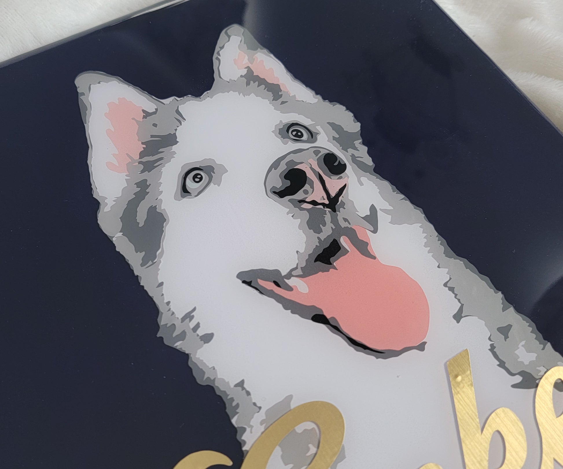 Portrait of a grey and white husky dog made with vinyl on a navy blue canvas background, sealed in epoxy resin with chrome gold vinyl name across the front.
