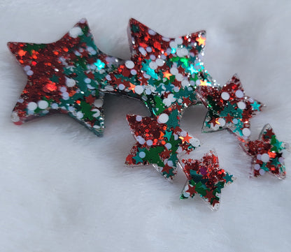 Six star shaped epoxy resin pieces filled with red and Christmas themed glitter, displayed on a white background.
