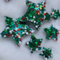 Six star shaped epoxy resin pieces filled with green and Christmas themed glitter, displayed on a white background.