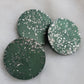 Three green circular epoxy resin pieces with silver glitter, on a white background.