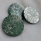 Three green circular epoxy resin pieces with silver glitter, on a white background.