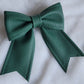 Dark green faux leather sailor bow displayed on a white fabric background.