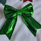 Green metallic faux leather sailor bow displayed on a white fabric background.