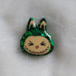 Labubu inspired small epoxy resin pet tag, made with green glitter and acrylic painted details.