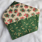 Handmade fabric pet bandana featuring stripes of Christmas holiday themed fabric in mistletoe prints, with gold colored metal rivets along one edge.