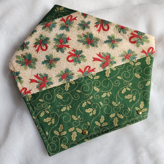 Handmade fabric pet bandana featuring stripes of Christmas holiday themed fabric in mistletoe prints, with gold colored metal rivets along one edge.