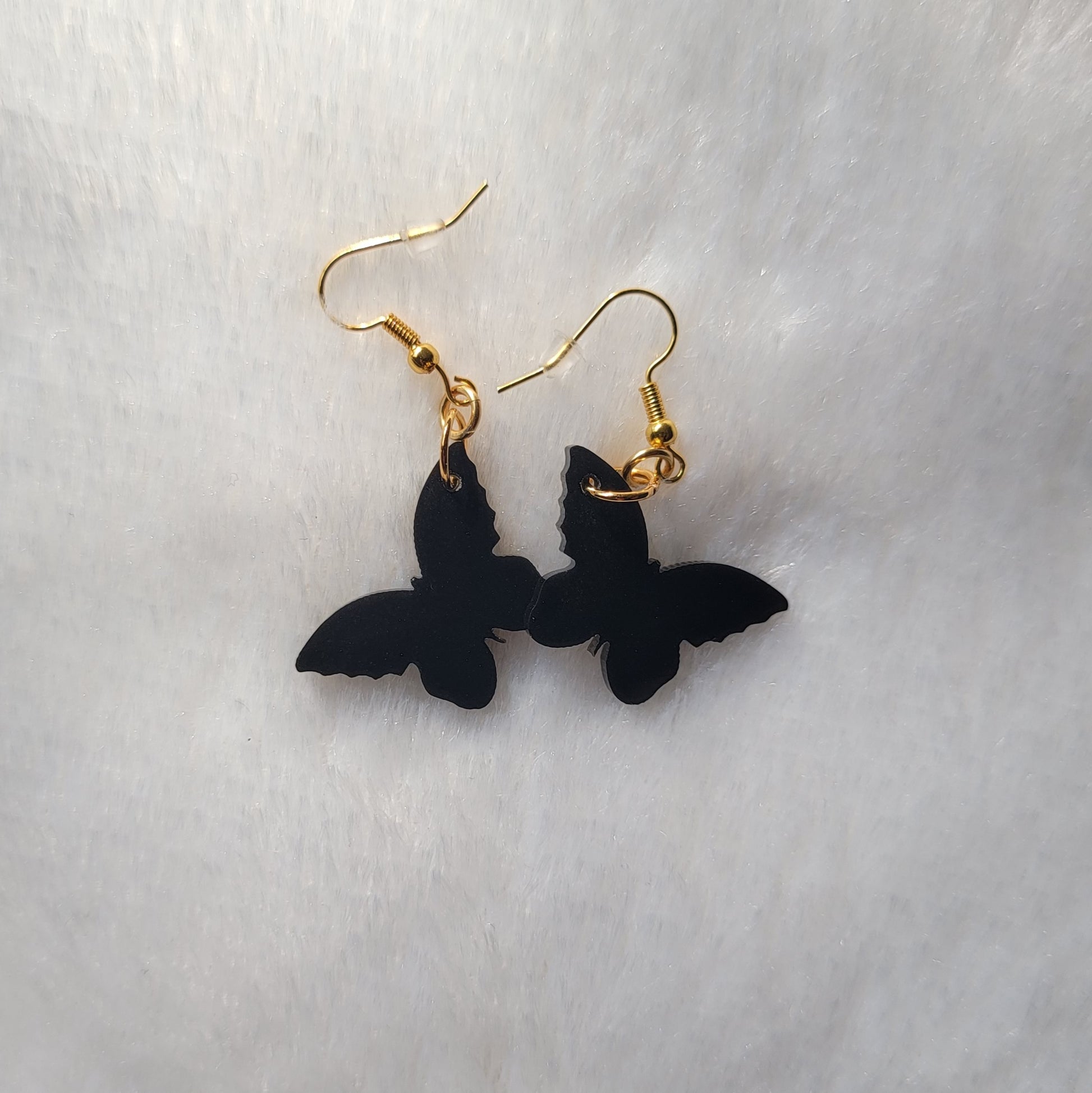 Small drop earrings made from black butterfly shaped epoxy resin pieces.