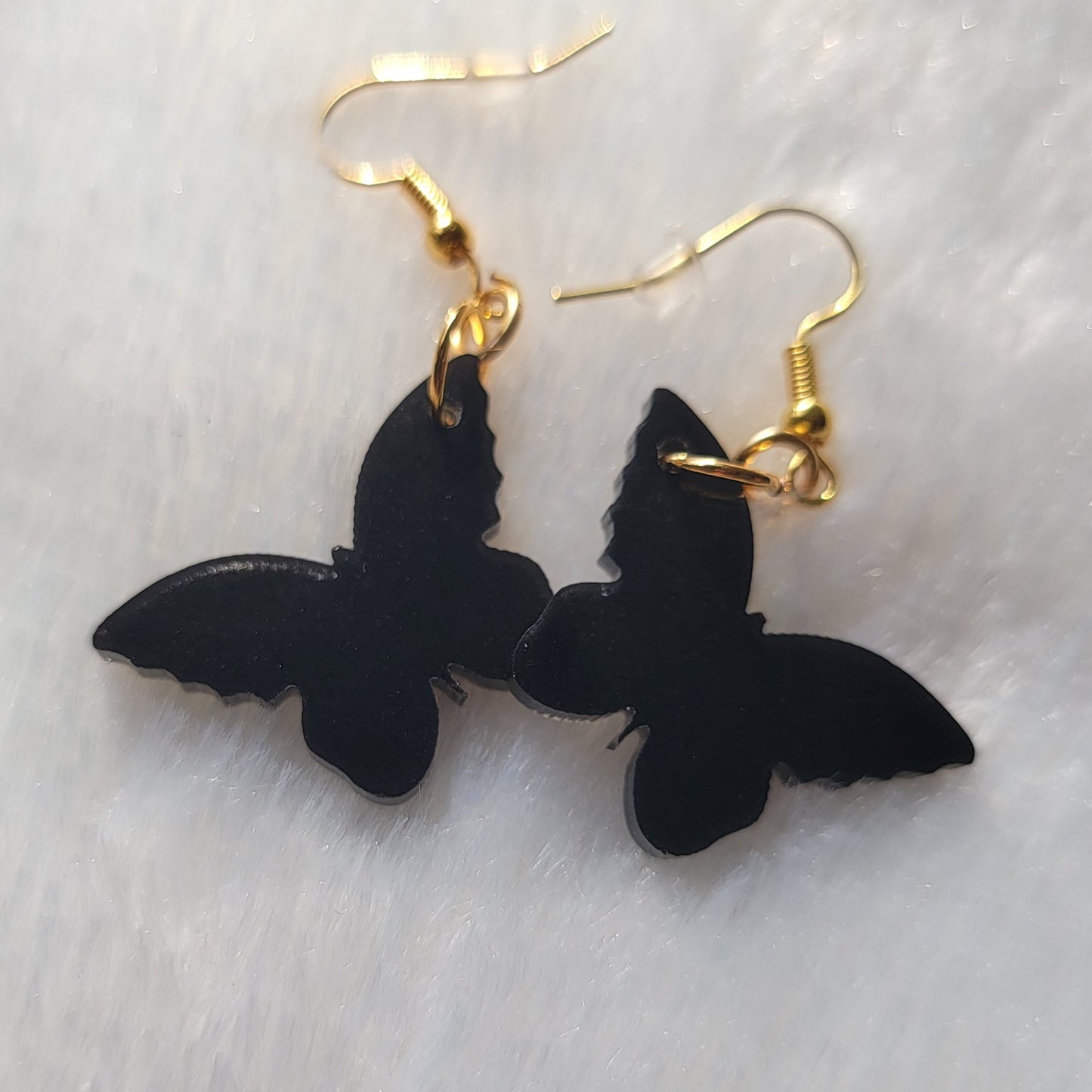 Small drop earrings made from black butterfly shaped epoxy resin pieces.