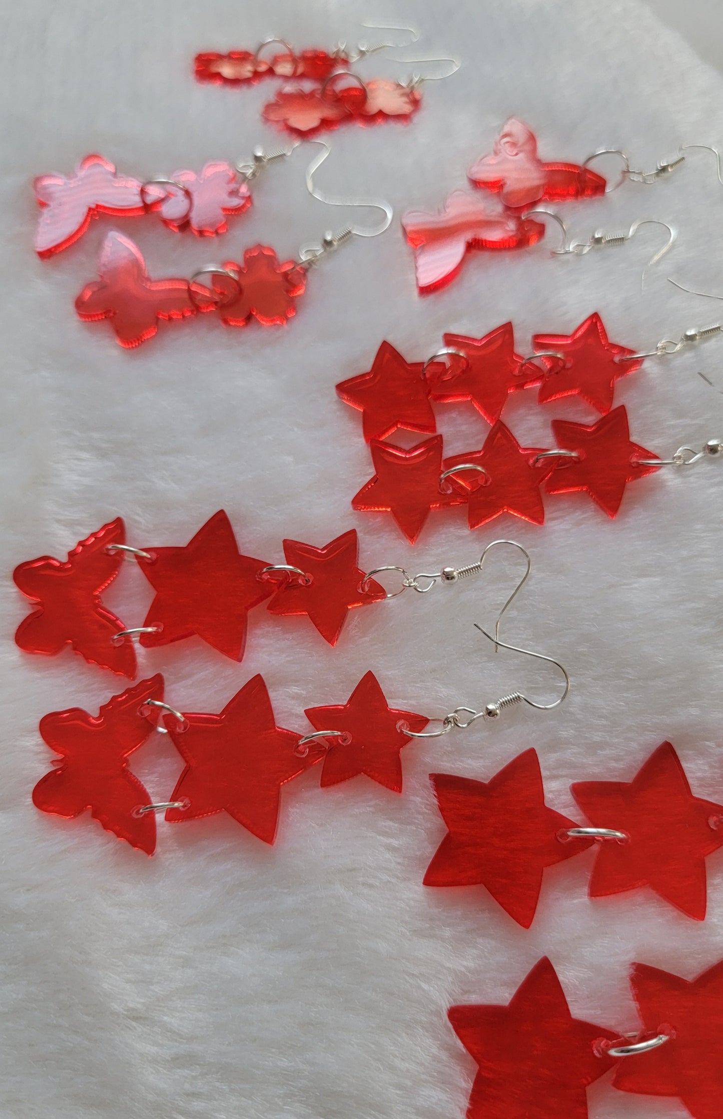 Array of red translucent epoxy resin drop earrings, including stars, flowers, and butterfly shapes.
