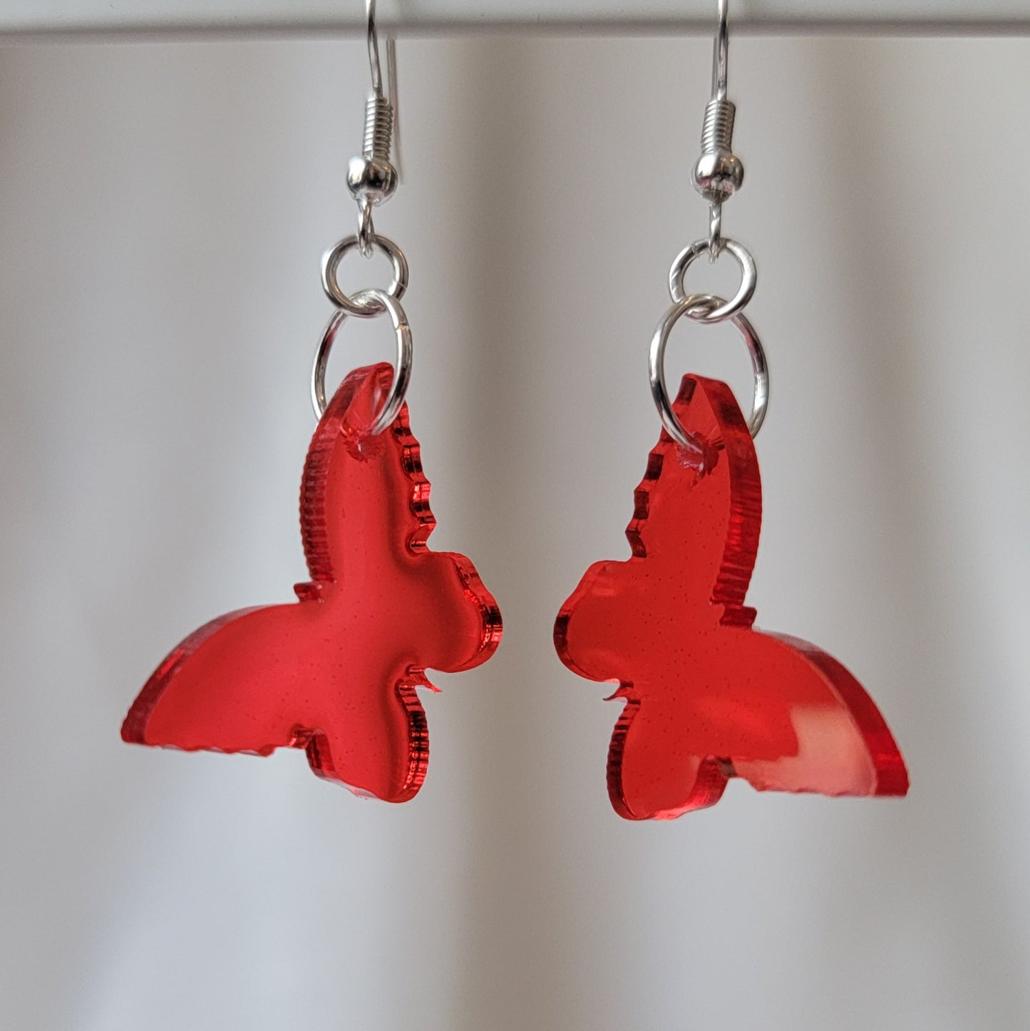 Small drop earrings made from red translucent butterfly shaped epoxy resin pieces.