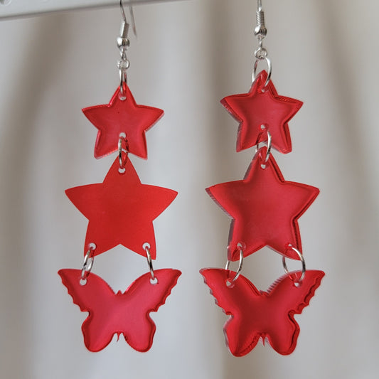 Three tiered drop earrings made from translucent red star and butterfly shaped epoxy resin pieces.