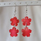 Two tiered drop earrings made from translucent red flower shaped epoxy resin pieces.