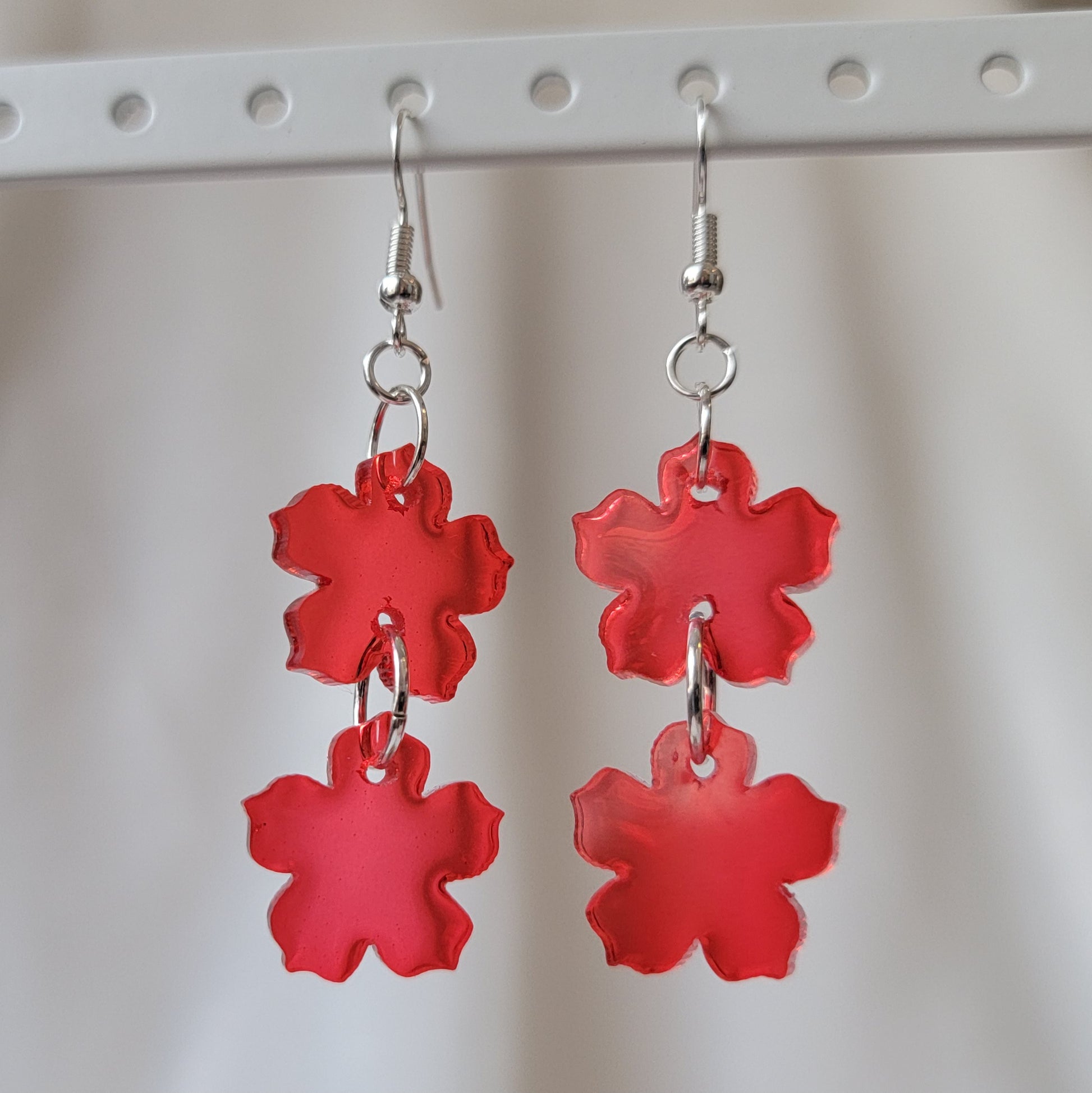 Two tiered drop earrings made from translucent red flower shaped epoxy resin pieces.