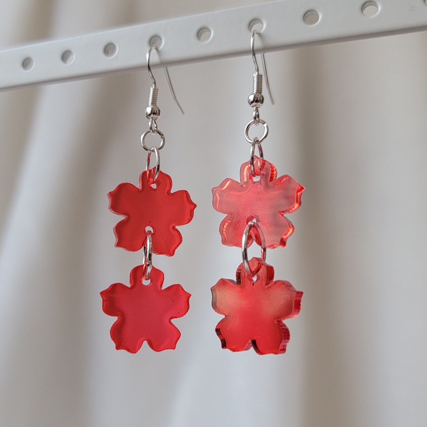 Two tiered drop earrings made from translucent red flower shaped epoxy resin pieces.