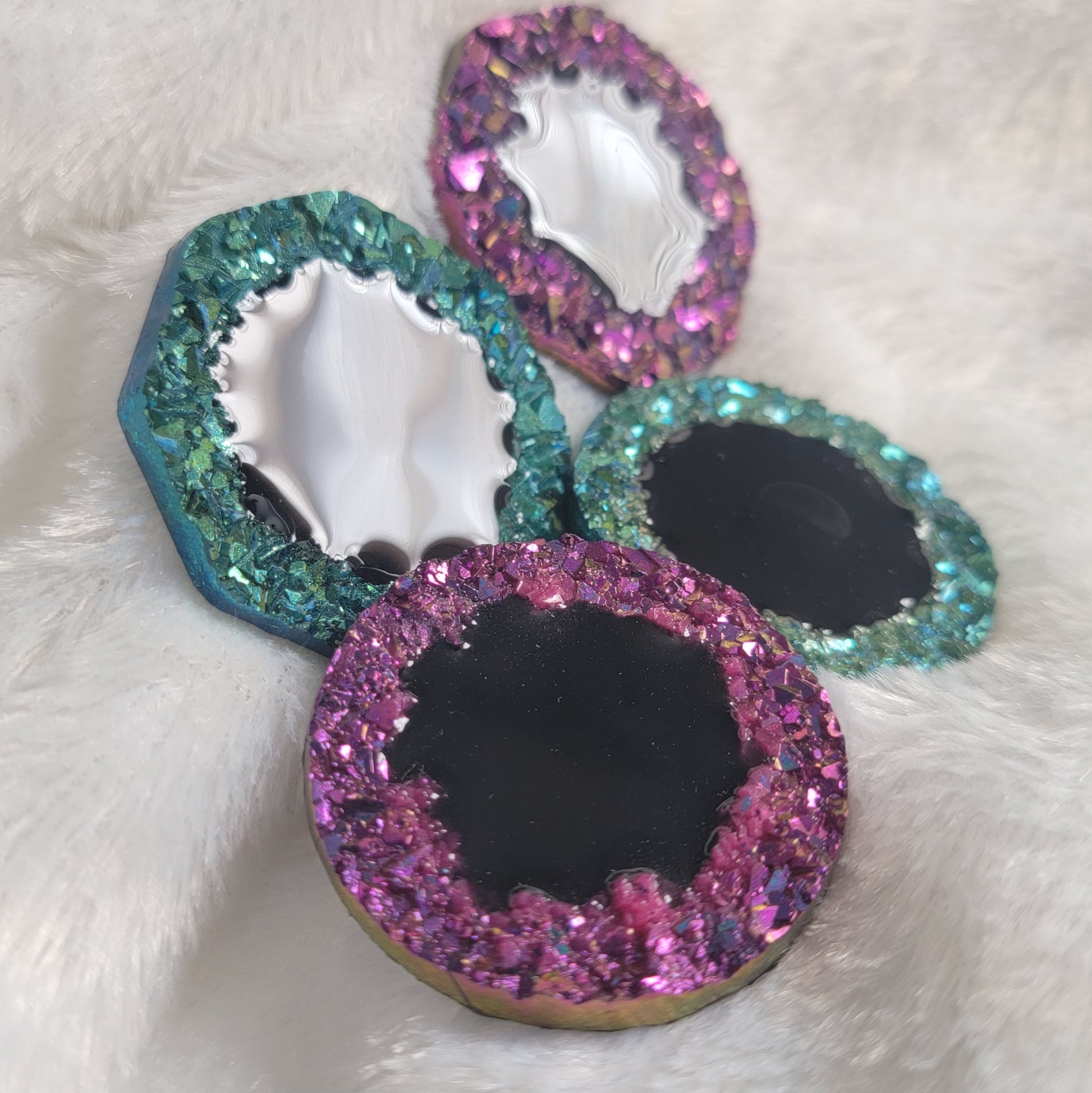 Four epoxy resin pieces with crystal texture edges, two green and two purple, with black centers.