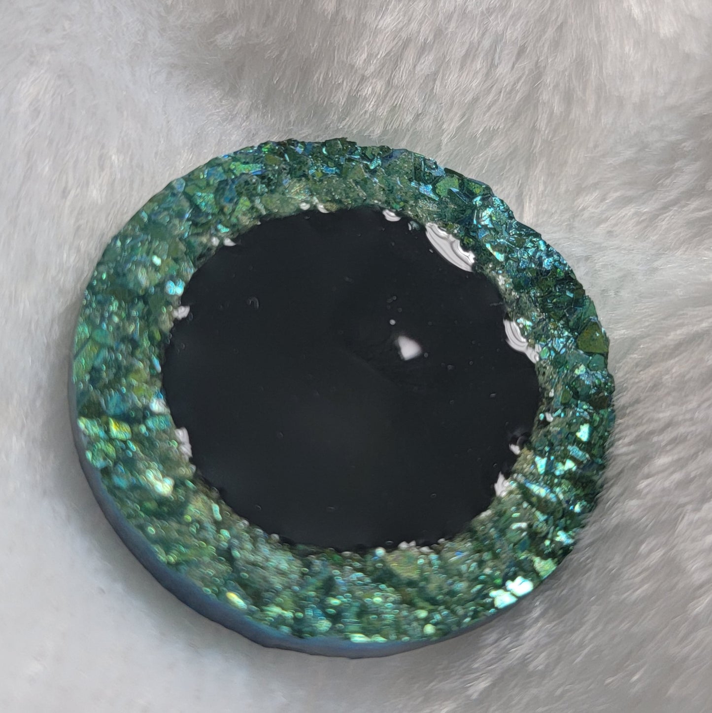 Round epoxy resin piece with green crystal texture border and black center, displayed on a white background.