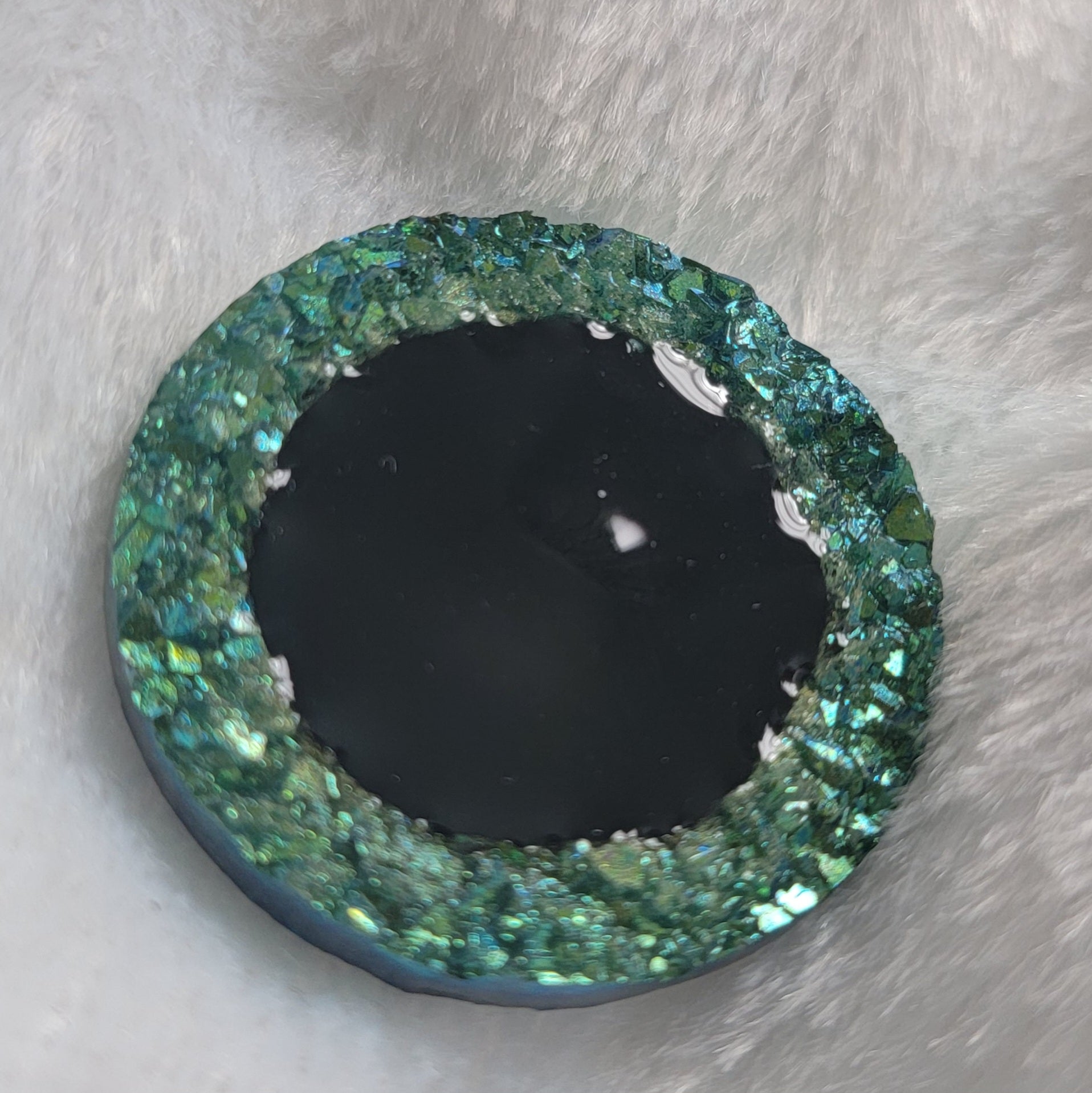 Round epoxy resin piece with green crystal texture border and black center, displayed on a white background.