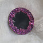 Round epoxy resin piece with purple crystal texture border and black center, displayed on a white background.