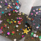 Close up of hexagon shaped epoxy resin pieces filled with assorted glitter shapes and silver or gold holographic bases.