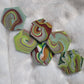Hexagon shaped epoxy resin pieces with swirling greens and rust colored pigments, displayed on a white background.