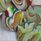 Hexagon shaped epoxy resin pieces with swirling greens and rust colored pigments, displayed on a white background.